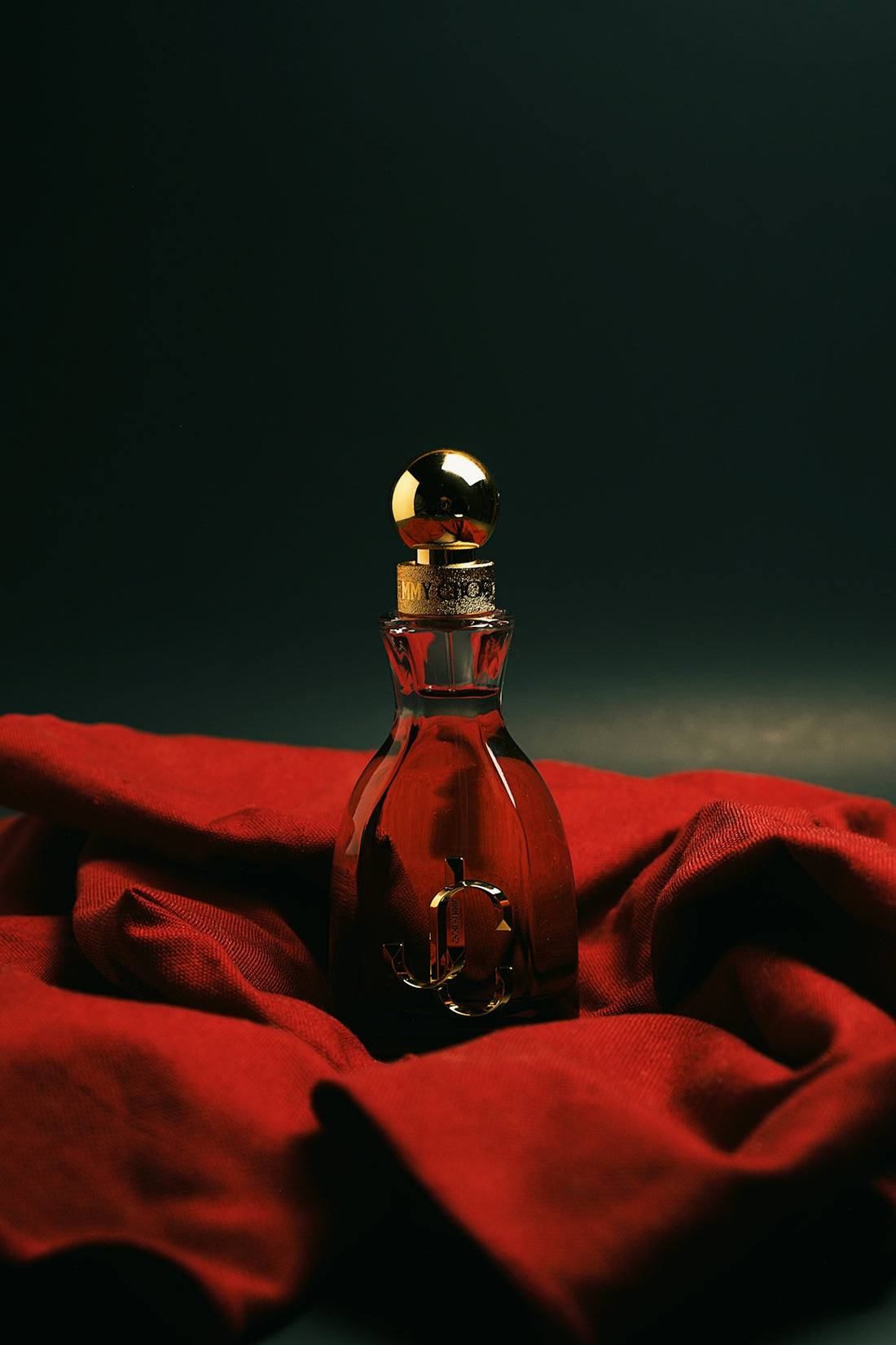 A bottle of perfume sitting on top of a red cloth